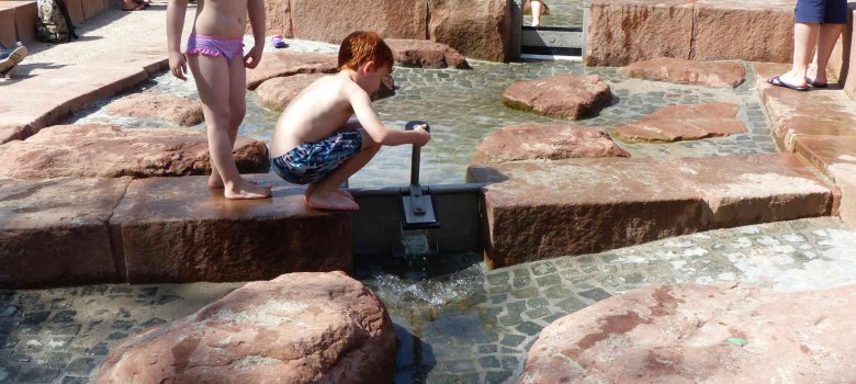 Wasserspielplatz Zwei Kinder spielen mit einer Wassersperre auf dem Wasserspielplatz in Contwig